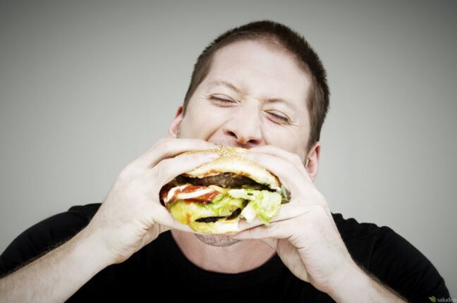 hombre caucasico comiendo una hamburguesa